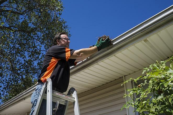 a person replacing a worn-out gutter on a building in Speonk